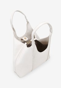 Bolso tote de cuero blanco con superficie texturizada, dos asas, parte superior abierta y un interior marrón. Presenta un cierre de presión de hardware dorado.