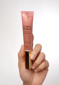 Revolution Pro Hydra Bright Cream Blush in een roze tube, met gouden accenten en een gladde, glanzende afwerking.