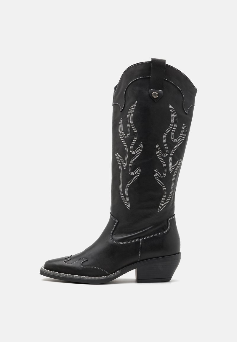 Μαύρη δερμάτινη καουμπόικη μπότες με λευκή ραφή σε σχήμα φλόγας, μυτερή μύτη και μεσαίο σκαλιστό τακούνι. Διαθέτει διακοσμητικό πάνω άκρο.