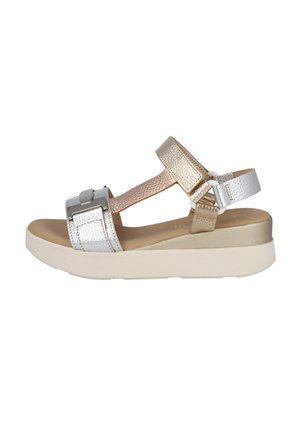 Sandalia de plataforma para mujer con tiras de cuero metálico en plata y oro, hebilla ajustable y suela gruesa blanca.