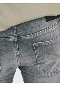 Jeans din denim gri cu buzunare pe spate, cusături vizibile și o textură netedă. Cureaua are un etichetă neagră, evidențiind un design casual.