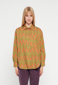 Πουκάμισο με μακριά μανίκια σε ελιά πράσινο χρώμα με γεωμετρικό μοτίβο κόκκινων τουλίπων και γραμμών. Διαθέτει μια τσέπη και στρογγυλεμένη ραφή στο τελείωμα.