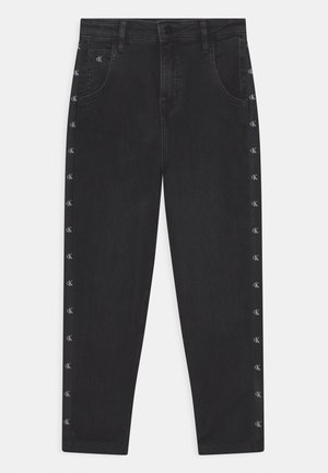 Pantalon en denim noir avec fermeture par bouton et fermeture éclair, poches avant, et petits logos blancs « cK » le long des coutures latérales extérieures.