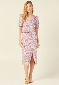 Blumiges Zweiteiler-Set mit einem kurzärmligen Oberteil und einem engen Rock mit einem seitlichen Schlitz. Farben sind Pink, Lila und mehrfarbige Akzente.