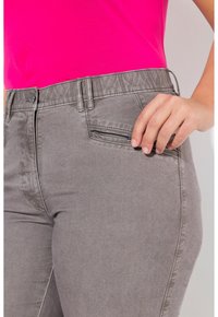 Graue Jeans aus weichem Stoff, mit einem eleganten Design, elastischem Bund und einer kleinen Reißverschlusstasche an der Seite.