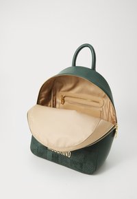 Grüner Kunstleder-Rucksack mit einem strukturierten unteren Abschnitt, goldenen Reißverschluss und beigem Innenfutter; beinhaltet eine Innentasche mit Reißverschluss.