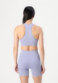 Ribbed lavender sports bra with a racerback design and matching high-waisted shorts, featuring a soft, textured fabric and fitted silhouette.
