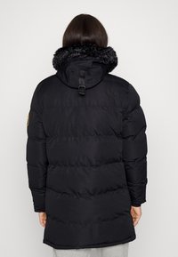 Abrigo acolchado negro con un cuello de piel sintética desmontable, secciones gruesas acolchadas y una cintura ajustada con capucha.