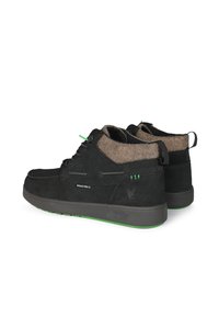 Botas de ante negras con un cuello de fieltro beige, acentos verdes y una suela de goma texturizada. Presentan un diseño de cordones y costuras reforzadas.