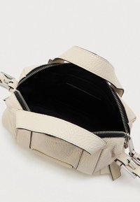 Bolsa de mão de couro texturizado bege claro com interior preto, com fecho de zíper aberto e alças curtas, em fundo branco liso.