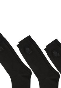 Fekete zoknik sima textúrával, bordázott mandzsettával és diszkrét logóval az oldalon. Nincs minta, egyszerű design.