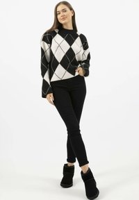 Zwart-wit geblokt patroon trui met een hoge halslijn, gecombineerd met zwarte slim jeans en zwarte enkellaarsjes. Zachte textuur en een losse pasvorm.