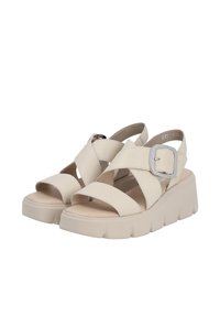 Sandales à plateforme beige avec des brides croisées, une grande boucle en argent et une semelle texturée pour l'adhérence. Doublure intérieure douce visible.