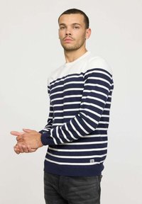 Pull en tricot rayé bleu marine et blanc avec un col rond, des manches longues et des bord-côtes ; comporte une petite étiquette logo à l'ourlet.