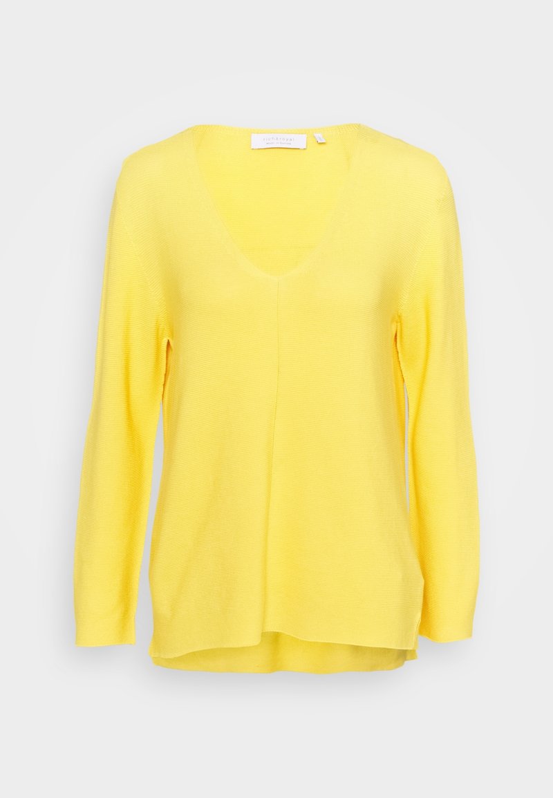 Pull en maille jaune à manches longues avec col en V et ourlet légèrement irrégulier, présenté sur fond blanc uni.