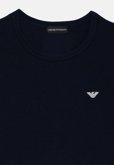 Mornarsko modra majica s kratkimi rokavi s krožnim izrezom, izdelana iz mehke tkanine, na prsih pa ima majhen belo vezen logotip.