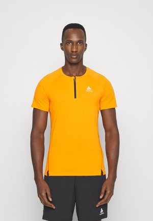 Oranges kurzes, ärmelloses Sporthemd mit einem schwarzen Reißverschluss, das aus strukturiertem Stoff besteht und ein Logo auf der Brust trägt. Kombiniert mit dunklen Shorts.