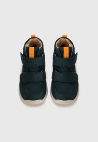 Dunkelgrüne Kleinkinderschuhe mit orangen Akzenten, ausgestattet mit zwei Klettverschlüssen, einem gepolsterten hellbraunen Innenfutter und einer Gummisohle.