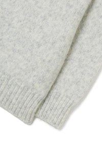 Nahaufnahme von weichen, hellgrauen Strickpullovern mit gerippten Bündchen, die die strukturierte Wolle und die kuschelige Stoffdetails zeigen.