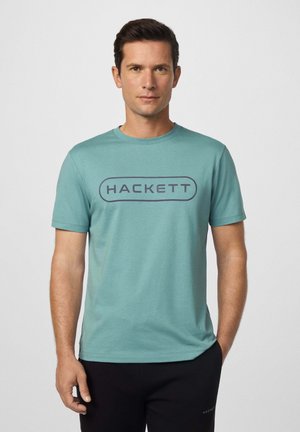 Camiseta de manga corta turquesa con el texto "HACKETT" en azul oscuro. Textura suave, escote redondo y corte relajado.