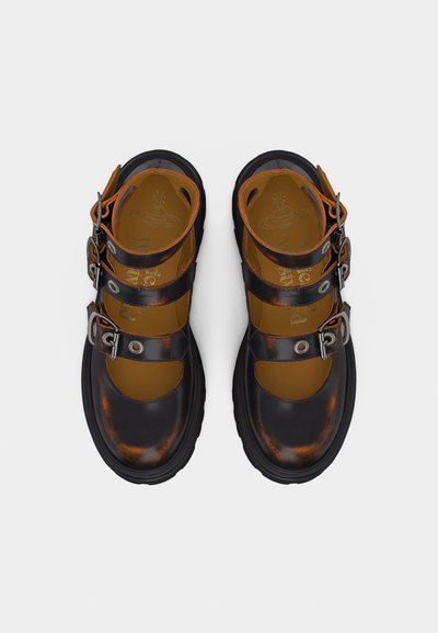 Μαύρα δερμάτινα παπούτσια Mary Jane με τρεις ρυθμιζόμενες λουρίδες με αγκράφες και παχύ πέλμα, εμφανιζόμενα από πάνω σε λευκό φόντο.