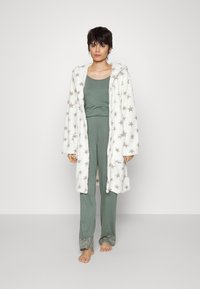 Gezellige witte badjas met grijze sterpatroon, in combinatie met een olijfgroen pyjama-overshirt en broek, voorzien van een patroon aan de manchetten en een capuchon. Zachte textuur.
