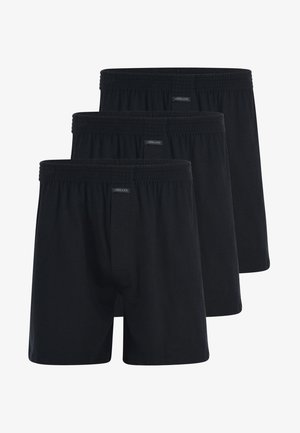 Schwarze Baumwollboxershorts mit elastischem Bund, offenem Hosenschlitz und glatter Textur. Drei Paare in einer Reihe ausgestellt.