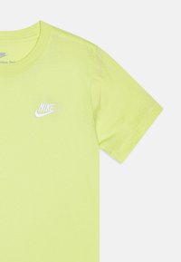 Rövid ujjú neon sárga Nike póló, bal mellen fehér hímzett logóval és kerek nyakkivágással. Puha pamut anyag.