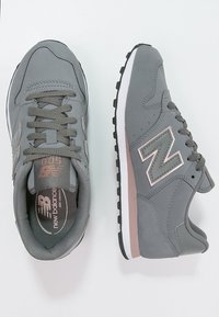 Baskets grises en matériau synthétique, dotées d'un col rembourré, d'une fermeture à lacets et d'une accent rose sur le côté. Semelle en caoutchouc pour une adhérence optimale.