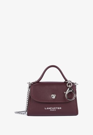 Sac à main en cuir bordeaux avec quincaillerie en argent, poignée supérieure et bandoulière en chaîne détachable. Présente le logo à l'avant et une fermeture à pression.