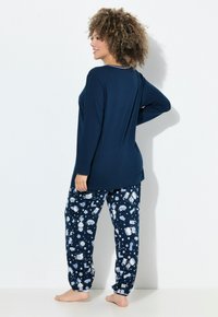 Top de manga larga azul marino con escote redondo; pantalones con estampado que presentan diseños en azul claro; ajuste holgado; tejido suave; puños elásticos en los tobillos.