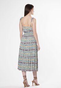 Multicolore maxi-jurk met een geometrisch patroon, verstelbare touwtjes en een getailleerde taille. De zoom is gelaagd voor extra textuur.