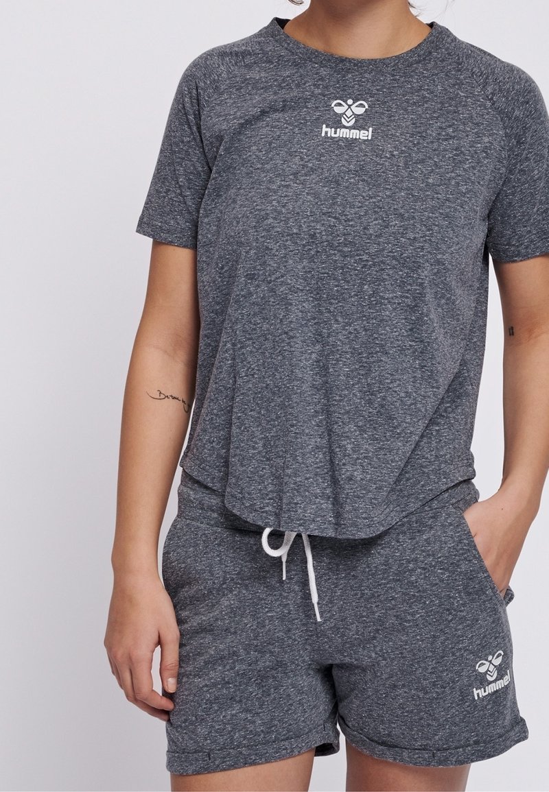 Šedý sportovní set trička a šortek vyrobený z texturované látky. Tričko má logo na hrudi a šortky mají šňůrku v pase a boční kapsy.