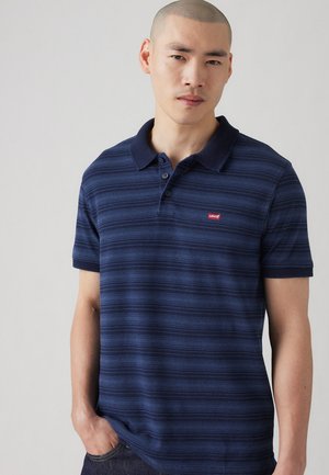 Navy blue striped polo shirt made of cotton, featuring a classic collar, three-button placket, and a small red Levi's logo on the chest.
