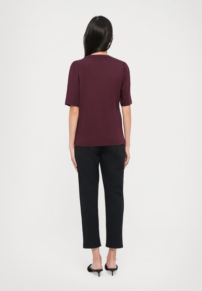 Maroon short-sleeve top with a round neckline, paired with black slim-fit trousers and black heeled mules. Smooth texture, simple design.
