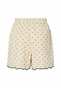Pantalones cortos de un beis claro con un patrón de ojos negros, cintura elástica y dobladillo con forma de concha. Hechos de una tela suave y texturizada.