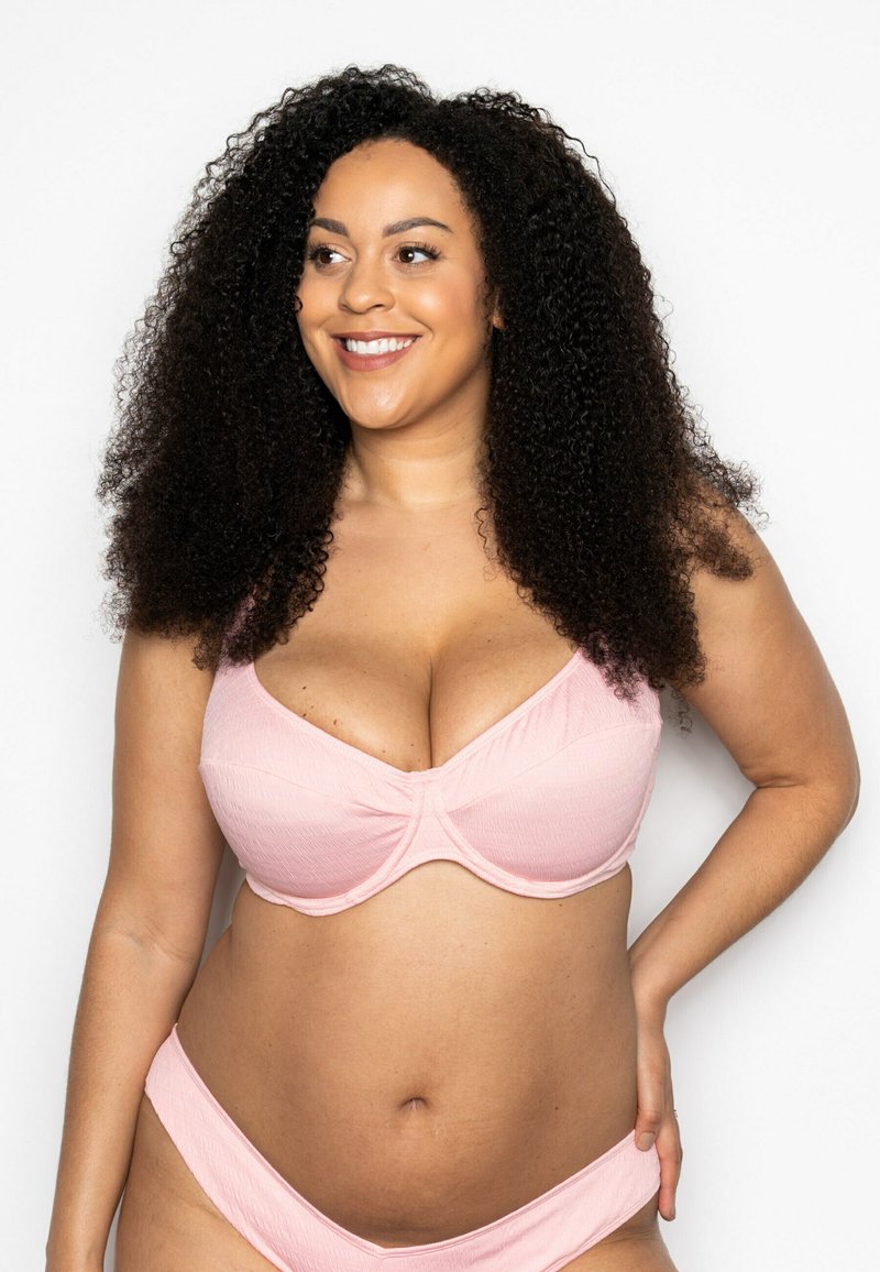 Light pink lingerie set with textured fabric. The bra features a wide band and underwire, paired with matching high-waisted briefs.