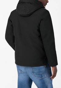 Schwarze Kapuzenjacke mit glatter Textur, mit einem teilweisen Reißverschluss, elastischen Bündchen und seitlichen Taschen, kombiniert mit blauen Jeans.