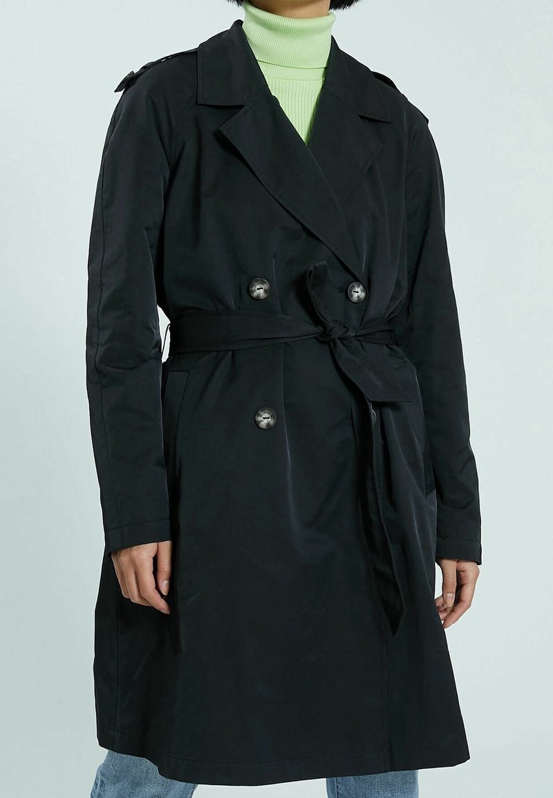 Czarny płaszcz trenchowy z podwójnymi guzikami, paskiem w talii i długimi rękawami. Gładki materiał i klasyczny design kołnierza.