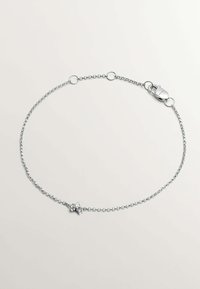 Pulsera de cadena de plata que presenta pequeños eslabones circulares y un cierre de langosta, adornada con un acento decorativo en el centro.