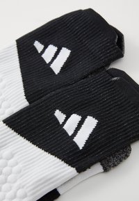 Calze bianco e nere con texture a coste, caratterizzate da un motivo geometrico distintivo e dettagli con logo. Design semimorbido per il comfort.