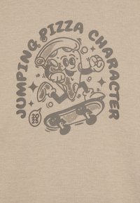 Maglietta beige con una grafica di un personaggio pizza cartoon che fa skateboard e il testo "PERSONAGGIO PIZZA RIMBALZANTE" in grigio scuro.