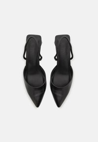 Mustat nahkaiset slingback-korkokengät, joissa on terävät varpaat, sileä pinta ja minimalistinen muotoilu. Varustettu ohuella takahihnalla ja leveillä aukkoilla.