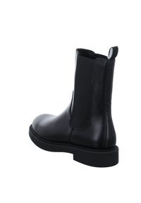 Botte Chelsea en cuir noir avec panneaux latéraux élastiques, languette à l’arrière et semelle épaisse en caoutchouc, vue en angle arrière trois quarts.