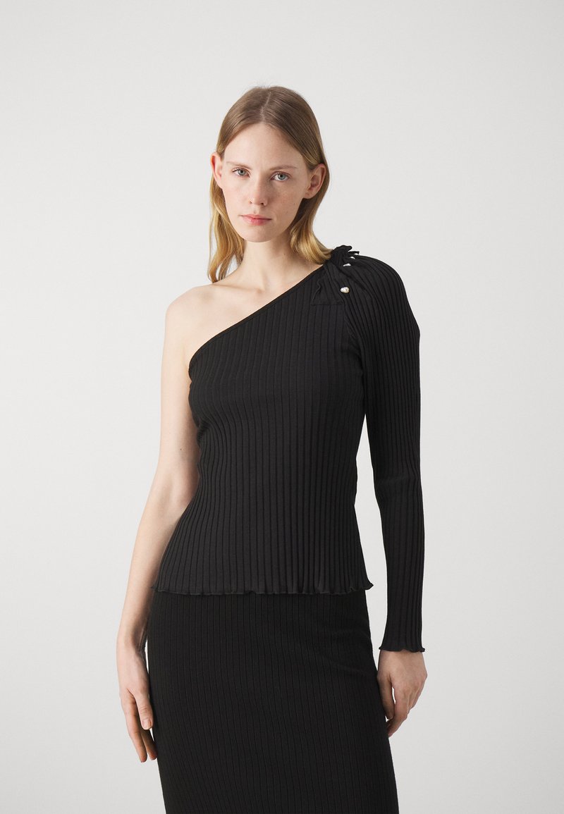 One-shoulder black ribbed top with long sleeve, featuring a ruffled hem and decorative buttons on the shoulder.