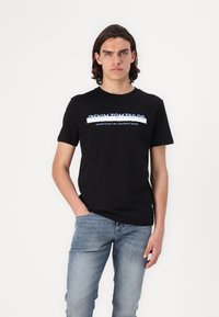 Sort bomulds T-shirt med rund hals, der har blå og hvide tekst "DENIM TOM TAILOR" og "etableret to tusinde syv" på forsiden.