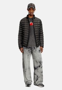 Black puffer jacket, gray top with red accent, gray patterned pants, black and white shoes, gray cap with branding, standing pose.