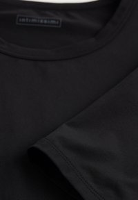 Camiseta negra de cuello redondo hecha de una tela suave, con mangas cortas, bordes limpios y un sutil logotipo en el cuello.