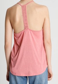 Roze mouwloze top met een hoge achterkant, voorzien van een kanten accent langs de halslijn en zacht, lichtgewicht materiaal dat mooi valt.