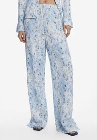 Pantalons légers et fluides, à motifs bleu et blanc, avec des rayures verticales et des accents floraux. Conception à jambes larges avec une taille confortable.